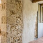 Rénovation d'un mur ancien en pierre naturelle avec enduit à la chaux clair et doublage intérieur sur ossature métallique.